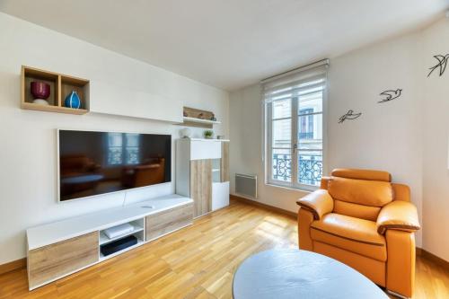 un salon avec une grande télévision et une chaise dans l'établissement Carlos logement au pied du Gros Horloge !, à Rouen