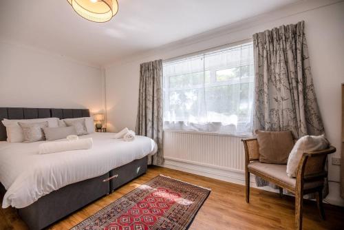 a bedroom with a bed and a chair and a window at Sunset Garden Cottage, Reydon in Reydon