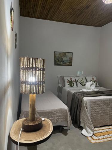 a bedroom with a bed and a table with a lamp at Pousada Luar de Caraíva in Caraíva