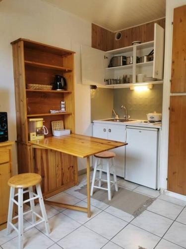 une cuisine avec une table en bois et deux tabourets dans l'établissement Cocon ski aux pieds et jolie vue, à La Salle Les Alpes