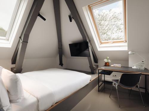 a bedroom with a bed and a desk and a window at Conscious Hotel Westerpark in Amsterdam