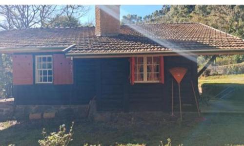 a small house with a red door and windows at Cabana Austríaca no Vale Encantado in Campos do Jordão