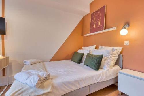 - une petite chambre avec un lit blanc et des oreillers verts dans l'établissement Mathilde Appartement proche Clinique Mathilde, à Rouen