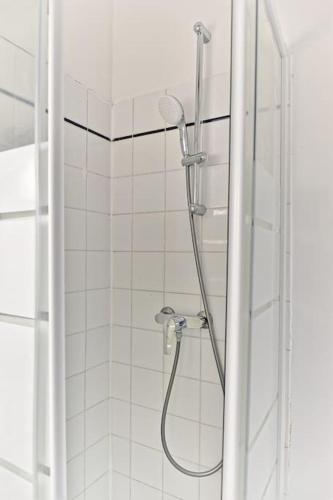 La salle de bains est pourvue d'une douche et de carrelage blanc. dans l'établissement Appartement charmant et coloré Montparnasse - II, à Paris