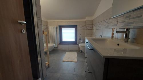 a bathroom with a sink and a toilet and a window at Agriturismo URLI in Magnano in Riviera