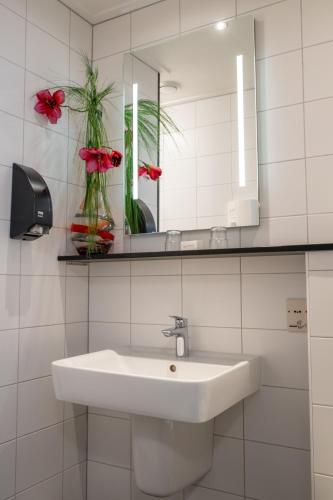 a bathroom with a sink and a mirror and flowers at Hotel Restaurant Het Witte Huis in Olterterp
