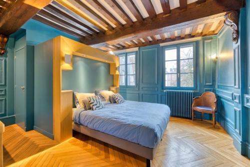 - une chambre avec des murs bleus, un lit et une chaise dans l'établissement Jehanne L'élégance Médiévale, à Rouen