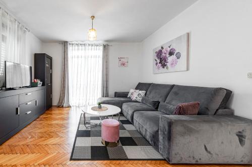 ein Wohnzimmer mit einer grauen Couch und einem Tisch in der Unterkunft Villa Nick in Cavtat