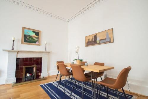 a dining room with a table and chairs and a fireplace at Stunning 3 Bed Flat in the Heart of the West End in Glasgow