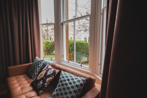a couch with pillows sitting in front of a window at Stunning 3 Bed Flat in the Heart of the West End in Glasgow