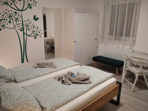 a bedroom with two beds and a tree on the wall at EszE Vendégszoba in Tata