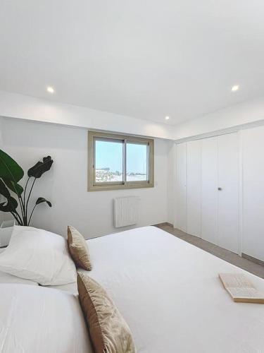 une chambre blanche avec un grand lit avec une fenêtre dans l'établissement Évasion Mer & Vue Imprenable, à Saint-Laurent-du-Var