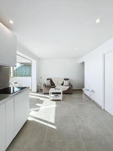 Il comprend une cuisine blanche et un salon avec un canapé. dans l'établissement Évasion Mer & Vue Imprenable, à Saint-Laurent-du-Var