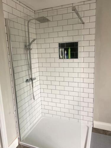 a bathroom with a shower with a white tile wall at Fully refurbished house Belfast in Belfast