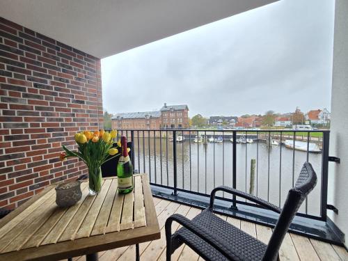 a balcony with a table with flowers and a bottle of wine at Ferienwohnung NorderHafen in Norden