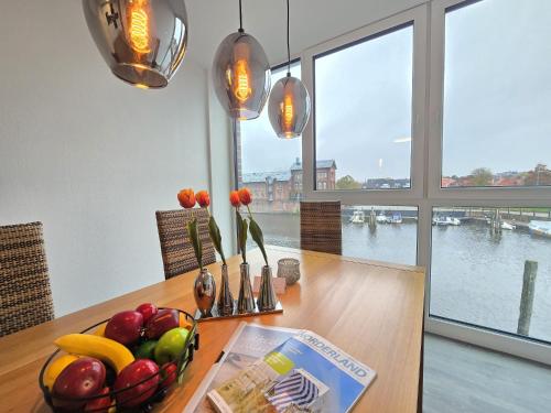 a table with a bowl of fruit and flowers on it at Ferienwohnung NorderHafen in Norden