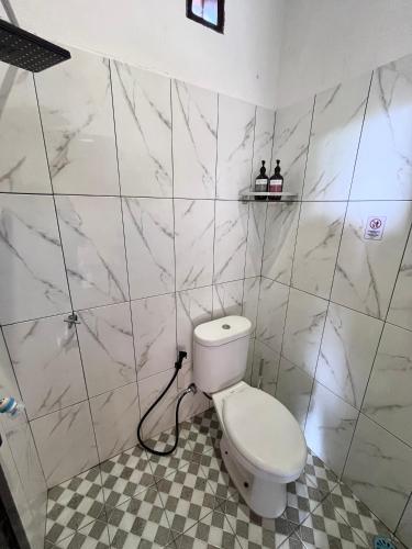 a white toilet in a bathroom with marble walls at Joglo Homestay Banyuwangi in Banyuwangi