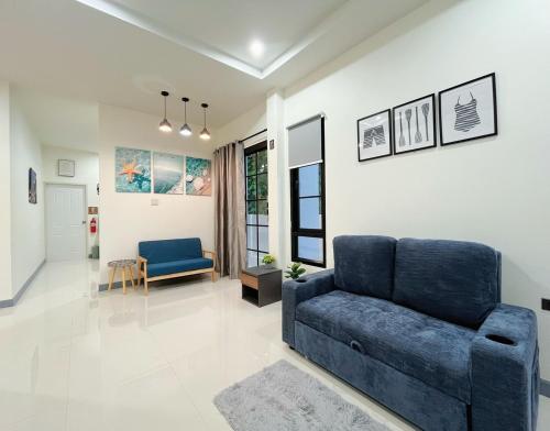 a living room with a blue couch and a chair at DelZiaNa Bara Villa Pakbara Satun พักได้ 6 ท่าน in Satun