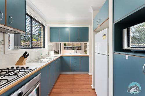a kitchen with blue cabinets and white appliances at Comfort and Style 2-Bed Townhouse in Ingleburn in Ingleburn