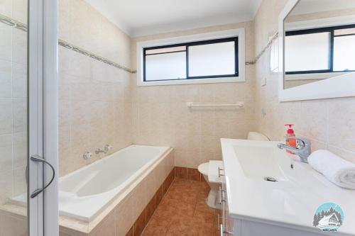 a bathroom with a tub and a sink and a toilet at Comfort and Style 2-Bed Townhouse in Ingleburn in Ingleburn