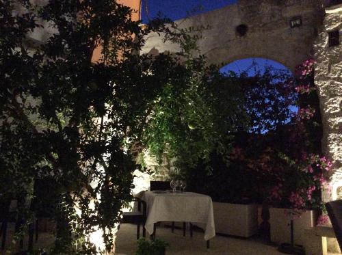 a table with a white table cloth sitting under a tree at Palazzo Muro Leccese Relais de Charme & Wellness in Muro Leccese