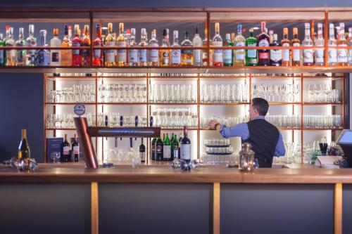 a bartender behind a bar with bottles of alcohol at Garner Hotel Elmshorn by IHG in Elmshorn