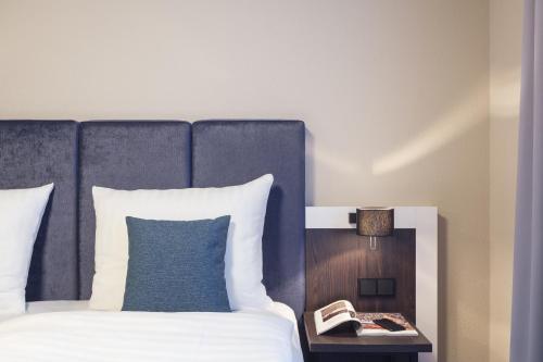 a bedroom with a bed with a blue headboard and a phone at Garner Hotel Elmshorn by IHG in Elmshorn
