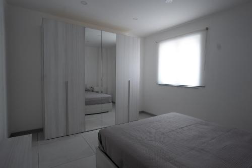 a white bedroom with a bed and a window at Capri Residence in Casoria