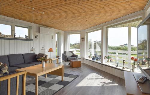 a living room with a couch and a table and windows at Pet Friendly Home In Hvide Sande in Hvide Sande