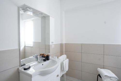 a white bathroom with a sink and a mirror at Capri Residence in Casoria