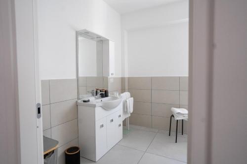a white bathroom with a sink and a mirror at Capri Residence in Casoria