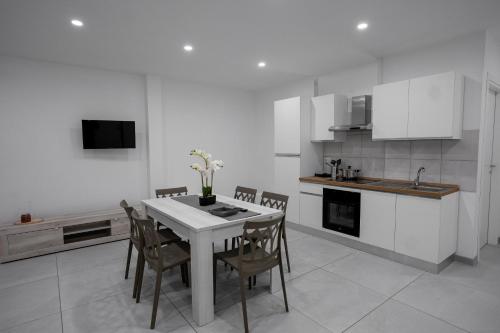a white kitchen with a table and chairs and a sink at Capri Residence in Casoria