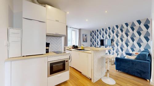 a kitchen with white cabinets and a blue couch at 869-Suite Bleuet - Superbe Appartement in Montreuil