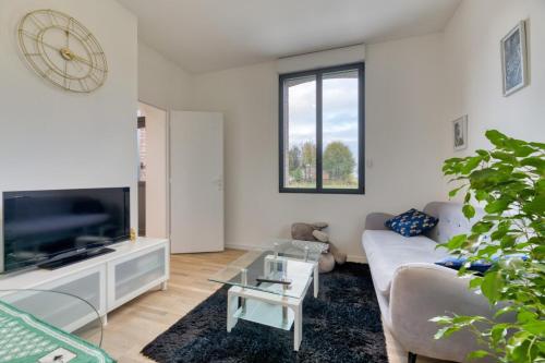 un salon avec un canapé et une télévision dans l'établissement Le Hameau Paisible Maison de Campagne, à Butot