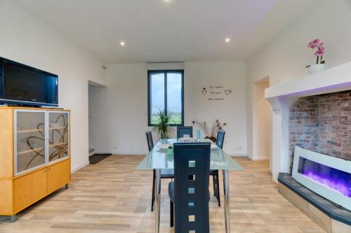 une salle à manger avec une table en verre et une cheminée dans l'établissement Le Hameau Paisible Maison de Campagne, à Butot