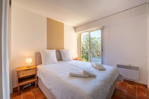 une chambre avec un grand lit blanc avec une fenêtre dans l'établissement Magnifique duplex avec terrasse et piscine, à Saint-Tropez