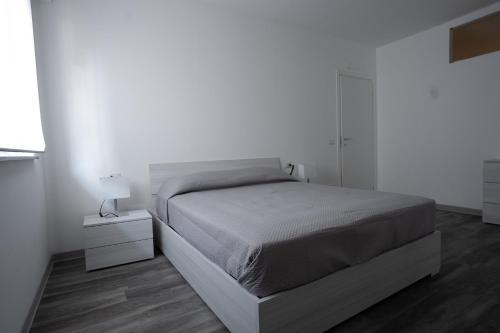 a white bedroom with a bed and a white wall at Capri Residence in Casoria