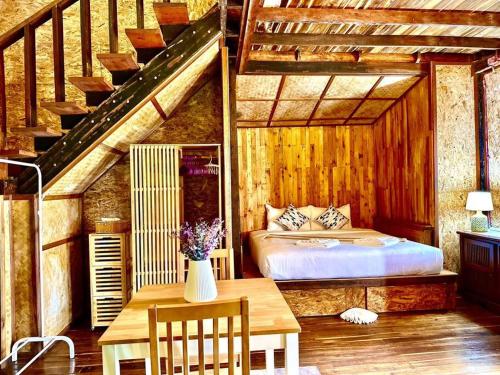 una camera con letto, tavolo e scale di Bangtao Wooden house resort and cafe a Ban Thalat Choeng Thale