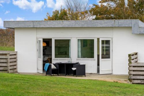 a white building with a table in front of it at Cozy Brenderup Apartment on the beach in Brenderup