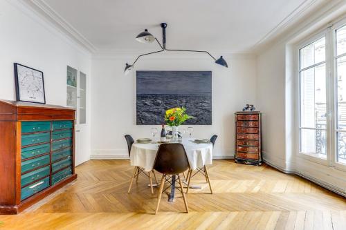 - une salle à manger avec une table et des fleurs dans l'établissement Le Penseur - Lumineux & proche Tour Eiffel, à Paris