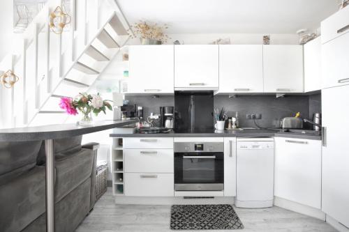 une cuisine blanche avec des placards blancs et un escalier dans l'établissement Les balcons des Ecréhous - Duplex front de mer, à Saint-Jean-de-la-Rivière