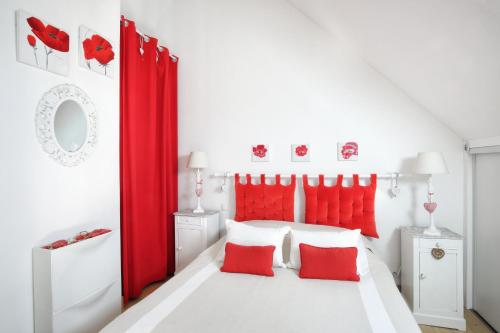 a bedroom with red curtains and a white bed with red pillows at Les balcons des Ecréhous - Duplex front de mer in Saint-Jean-de-la-Rivière