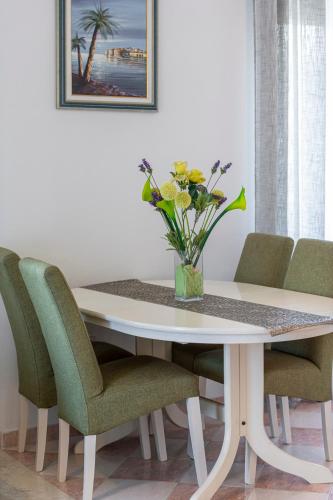 a dining room table with green chairs and a vase of flowers at Villa Nick in Cavtat