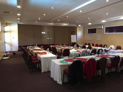 a room filled with tables and chairs with tablesearcher at Bethel Court Vineyard Hotel in Ezulwini