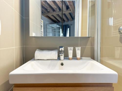 un lavabo blanc dans une salle de bain avec un miroir dans l'établissement St Michel - Deluxe Apartment - Harpe, à Paris
