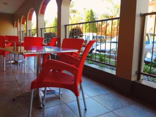 a restaurant with red chairs and tables and a balcony at Bethel Court Vineyard Hotel in Ezulwini