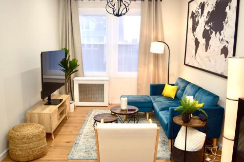 a living room with a blue couch and a tv at Newly Renovated 1 Bedroom Executive Apartment in Kearny