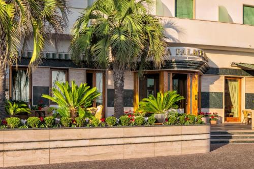 a restaurant with palm trees in front of a building at Astura Palace Hotel in Nettuno