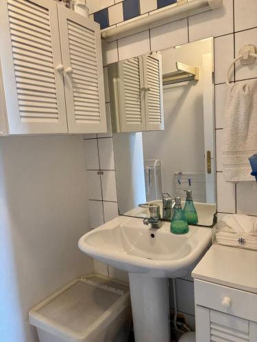 une salle de bain blanche avec un lavabo et un miroir dans l'établissement Chambre calme et lumineuse en plein coeur de Paris, à Paris