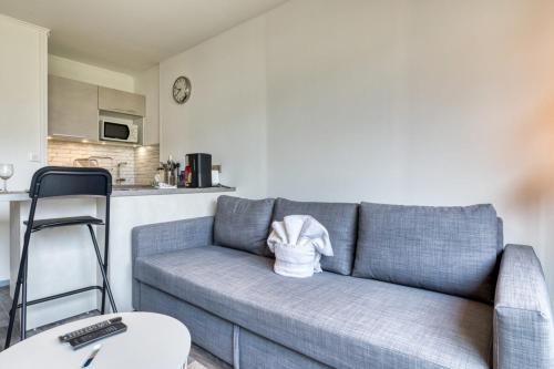 un salon avec un canapé bleu et une cuisine dans l'établissement Olivia studio avec Place de Parking, à Rouen